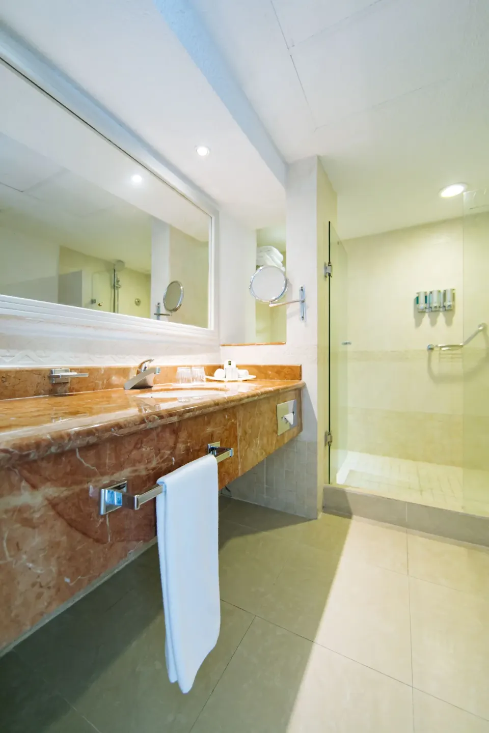 Bathroom with marble vanity and glass shower in a room at Occidental Costa Cancún.