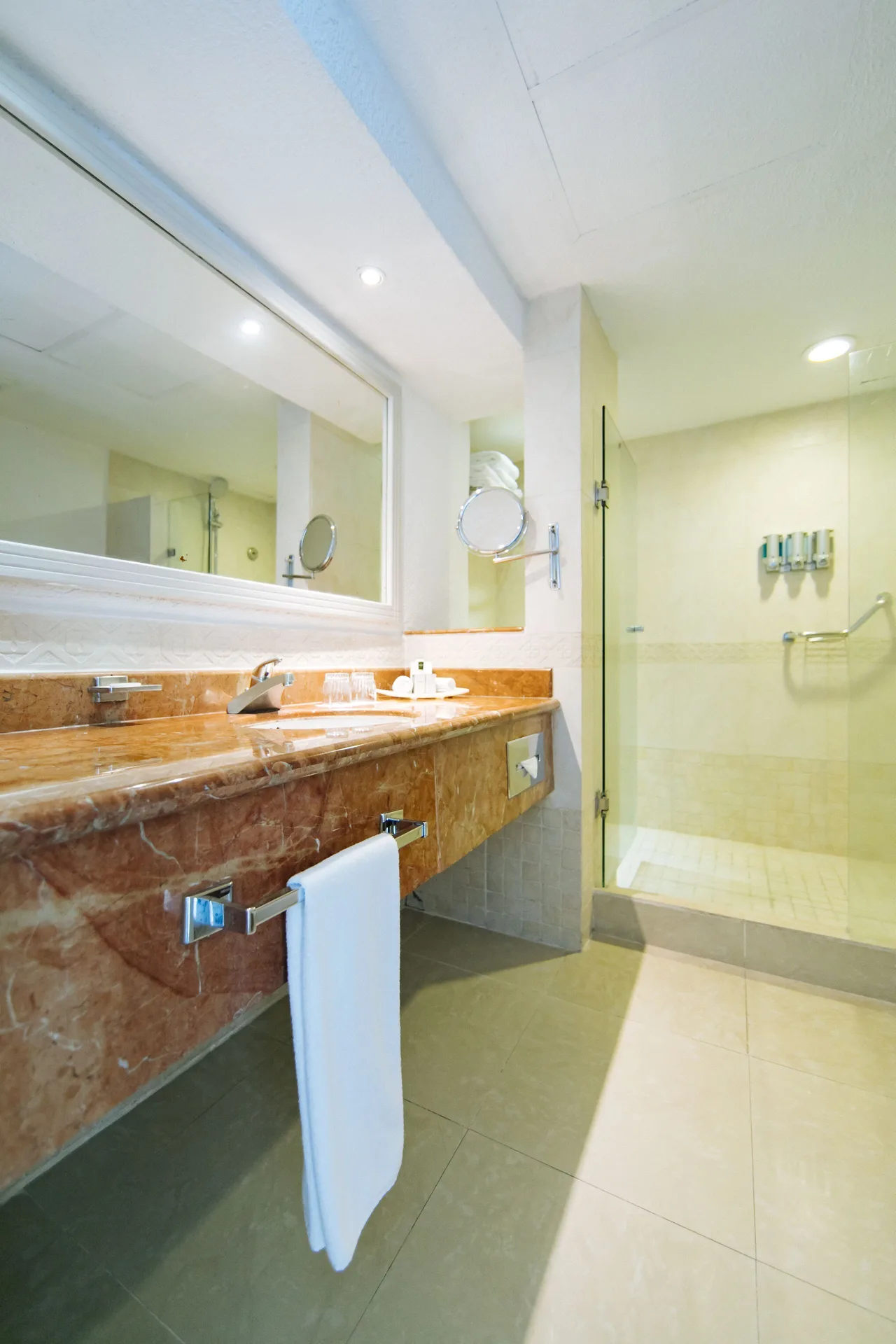 Bathroom with marble vanity and glass shower in a room at Occidental Costa Cancún.