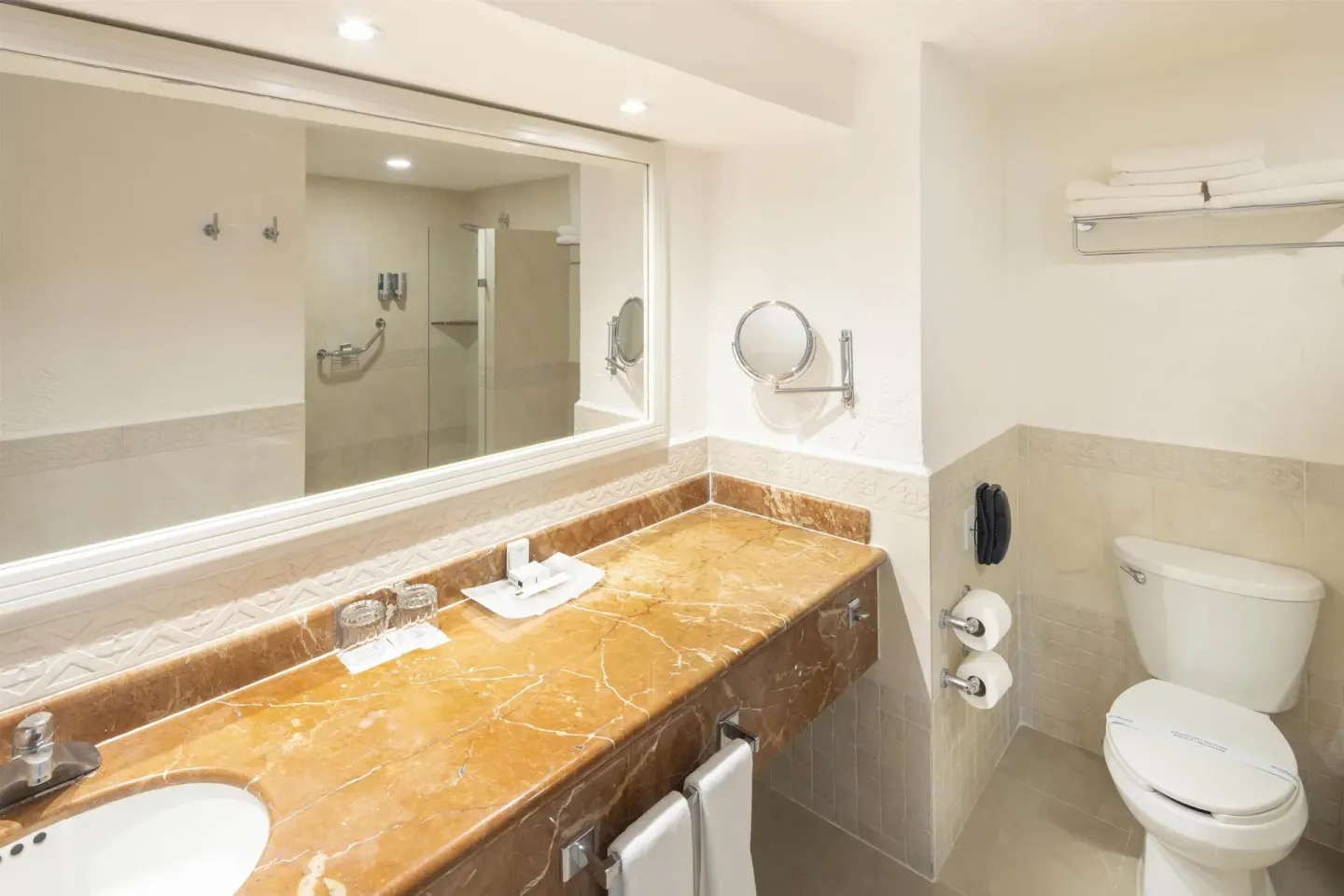 Guest room bathroom with marble vanity and toilet at Occidental Costa Cancún.