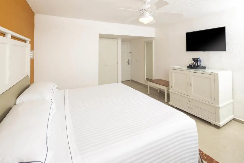 King bed guest room with TV and cabinet at Occidental Costa Cancún.
