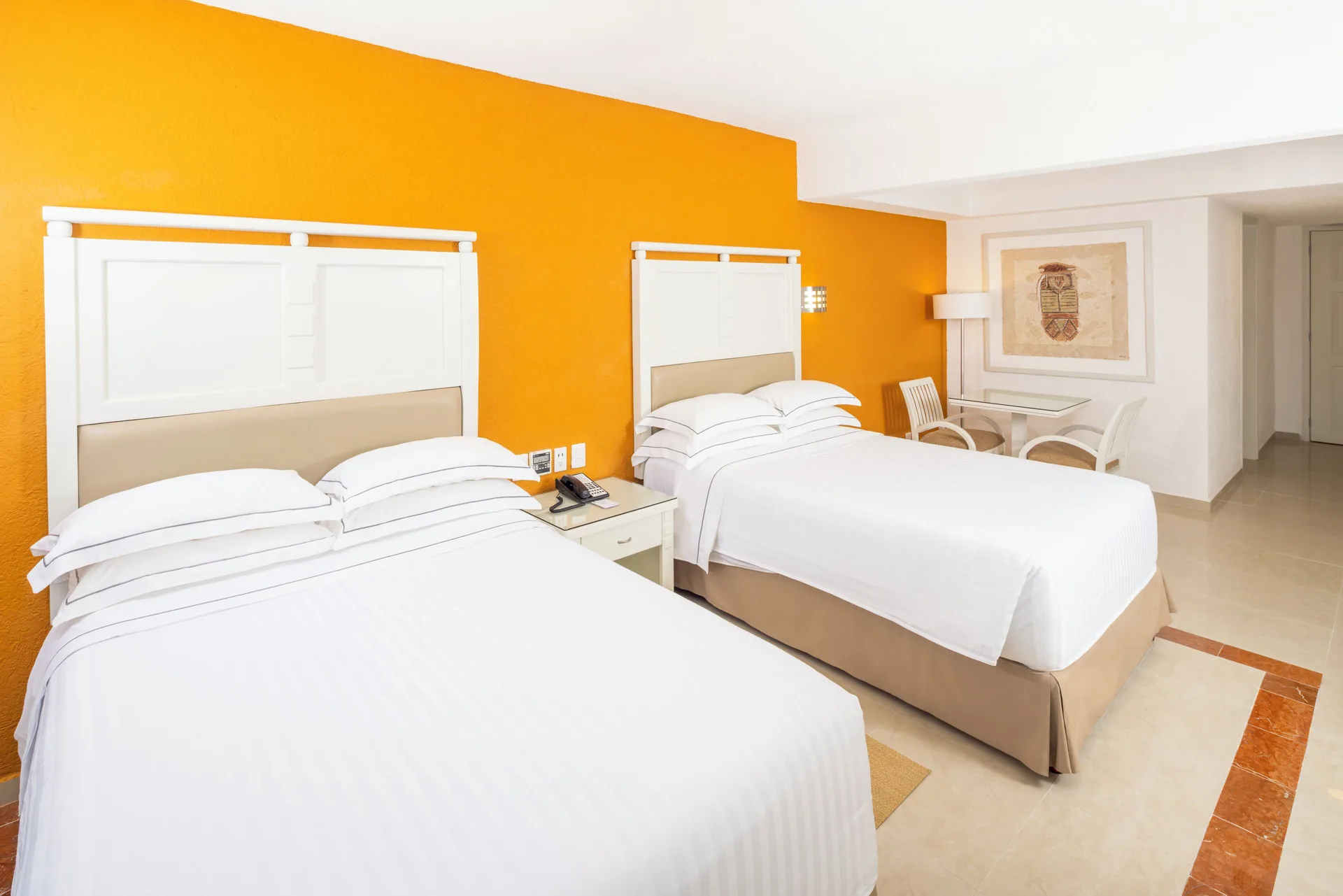 Two double beds and seating area in a guest room at Occidental Costa Cancún.