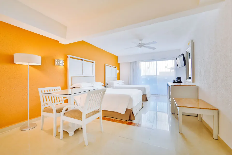 Two-bed guest room with seating and balcony light at Occidental Costa Cancún.