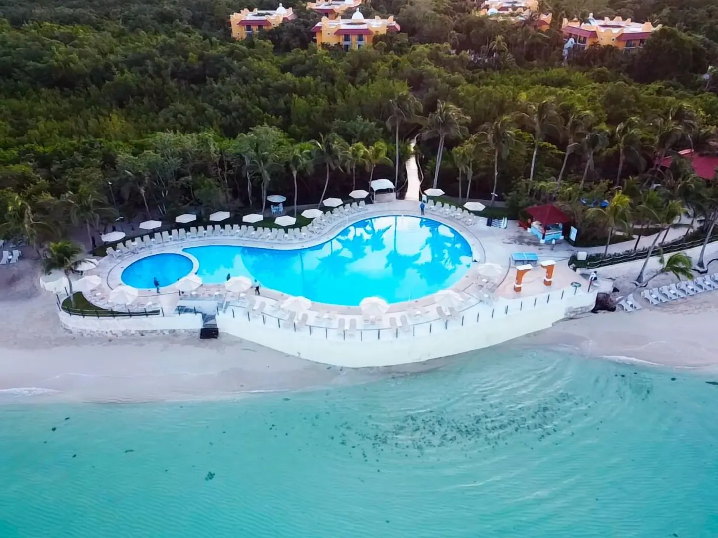 Aerial view of the beachfront pool, sandy beach, and turquoise sea at Occidental Cozumel.