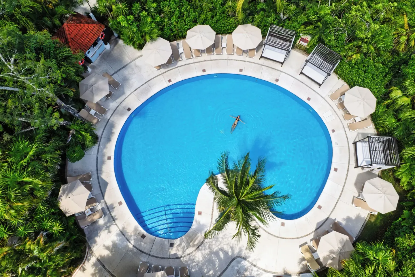 Aerial view of a round garden pool with loungers and umbrellas at Occidental Cozumel.