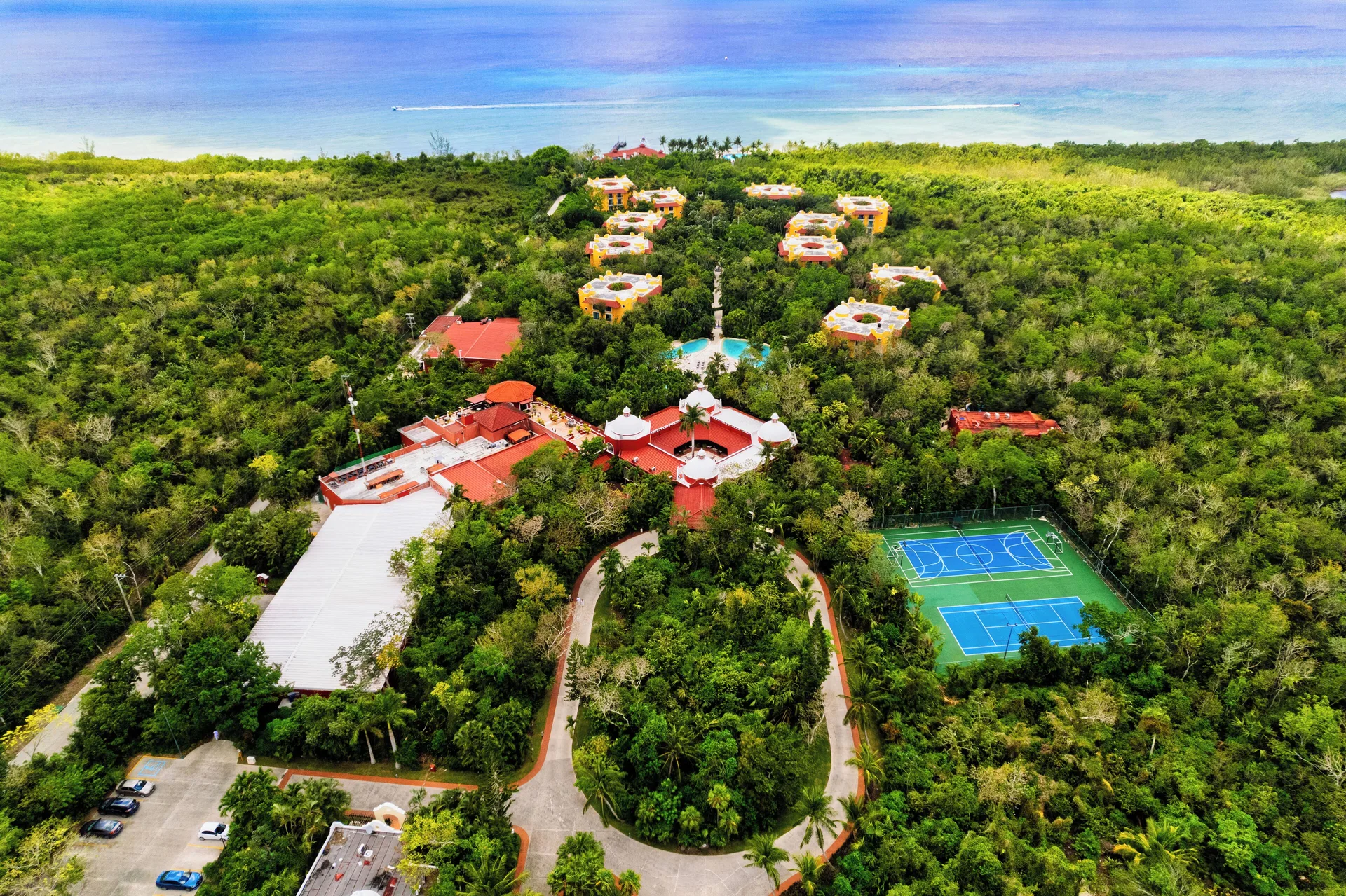 Aerial view of resort buildings, tennis courts, forest, and sea at Occidental Cozumel.
