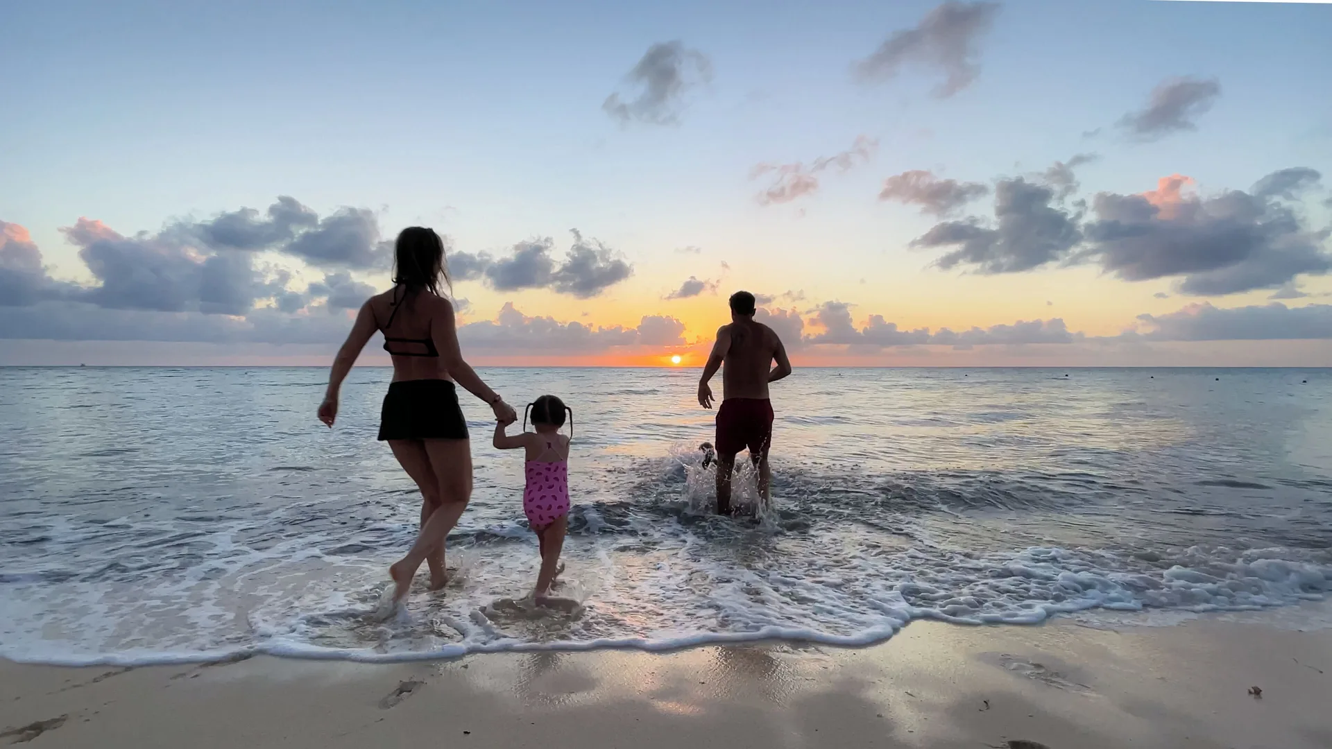 A family walks into the ocean at sunset at Occidental Cozumel.