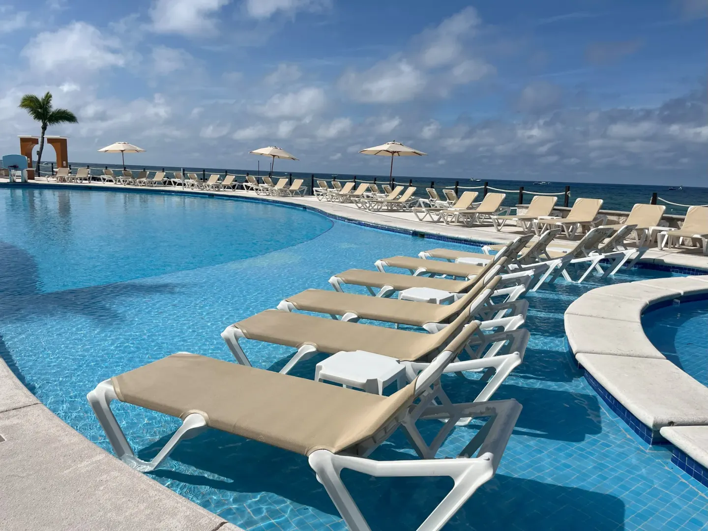 Pool loungers set in the shallow water with ocean views at Occidental Cozumel.