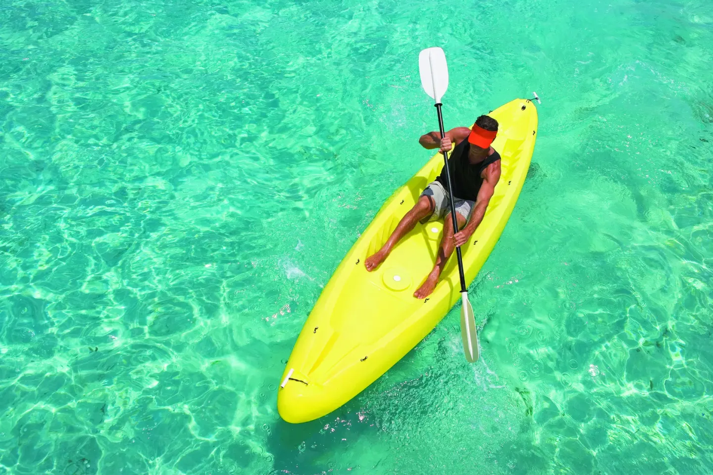 Person paddling a yellow kayak over clear turquoise water at Occidental Cozumel.