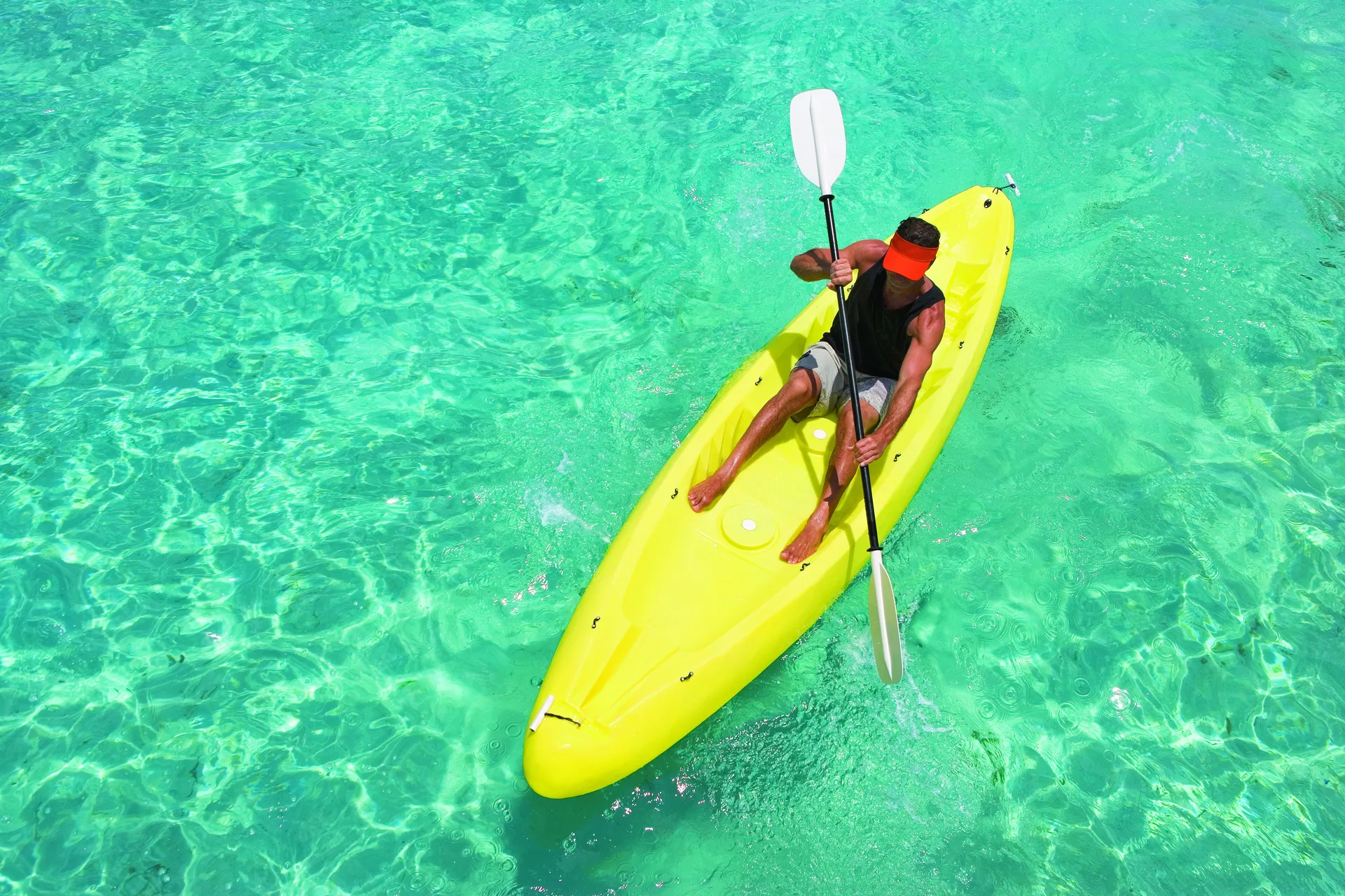Person paddling a yellow kayak over clear turquoise water at Occidental Cozumel.