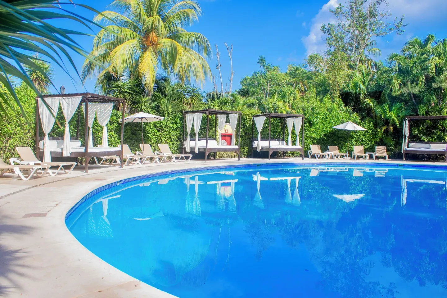 Pool edge with curtained cabanas and tropical greenery at Occidental Cozumel.