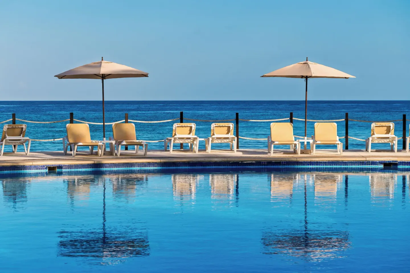 Pool edge with lounge chairs, umbrellas, and blue ocean beyond at Occidental Cozumel.