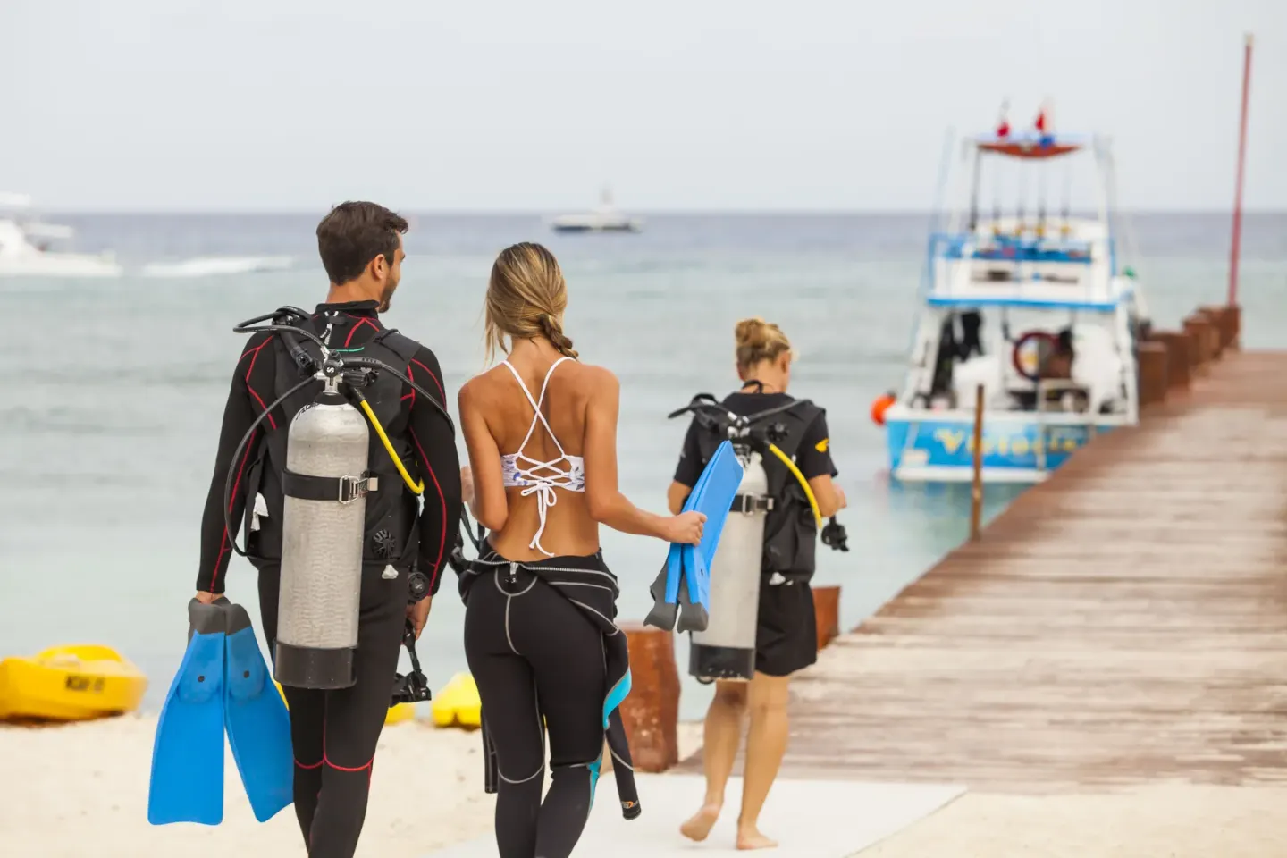 Scuba divers walking toward a pier and dive boat at Occidental Cozumel.