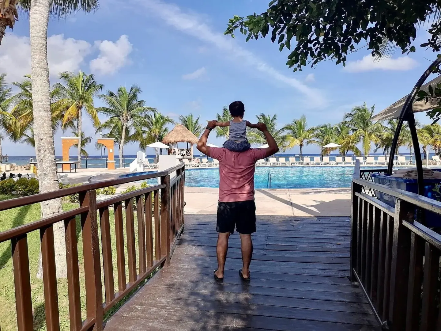 Adult carrying a child toward the oceanfront pool at Occidental Cozumel.
