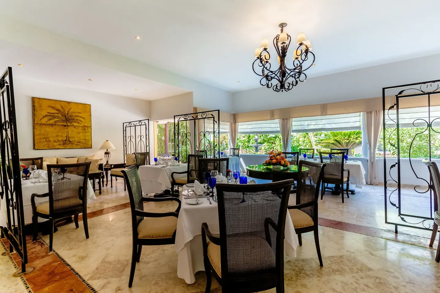 A bright dining room with white tablecloths and garden views at Occidental Cozumel.