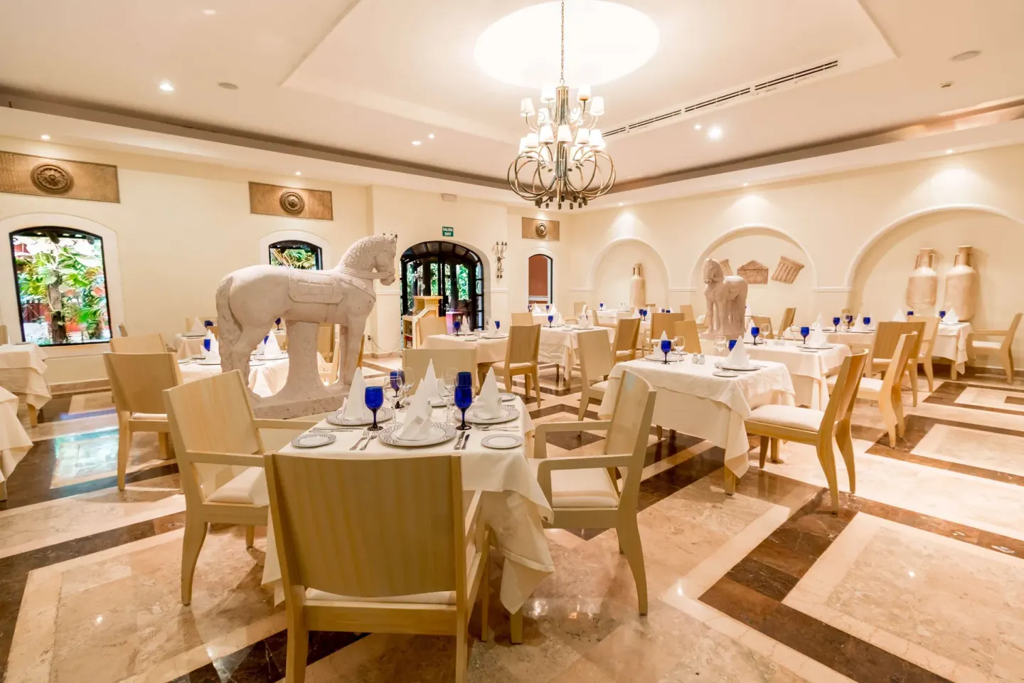 A cream-toned dining room with white horse sculptures at Occidental Cozumel.