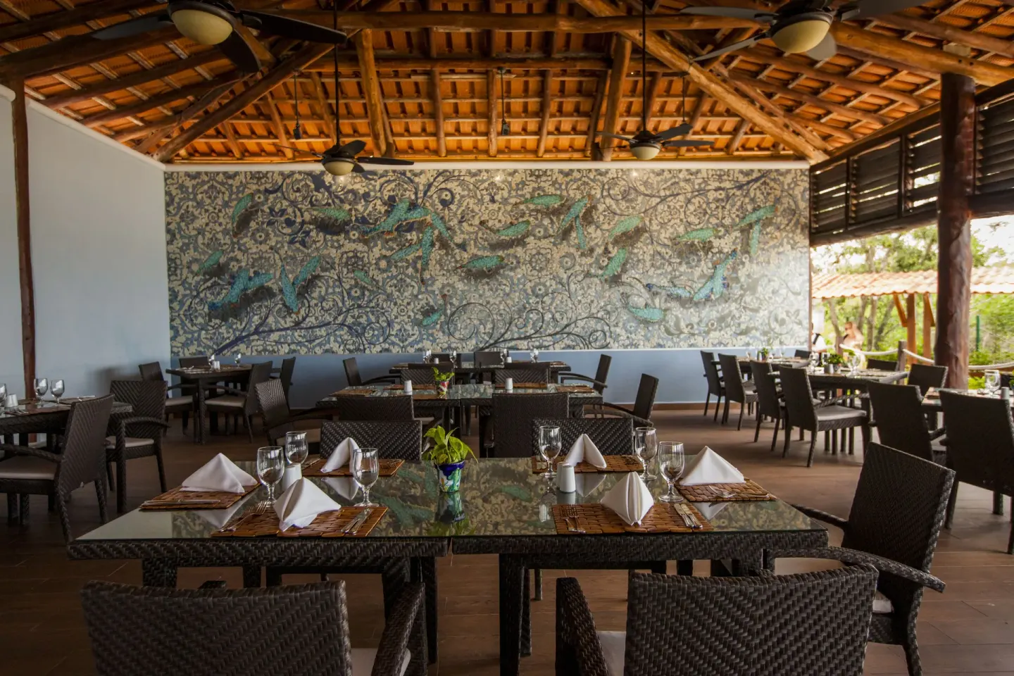 Open-air dining room with woven chairs and a fish mural at Occidental Cozumel.
