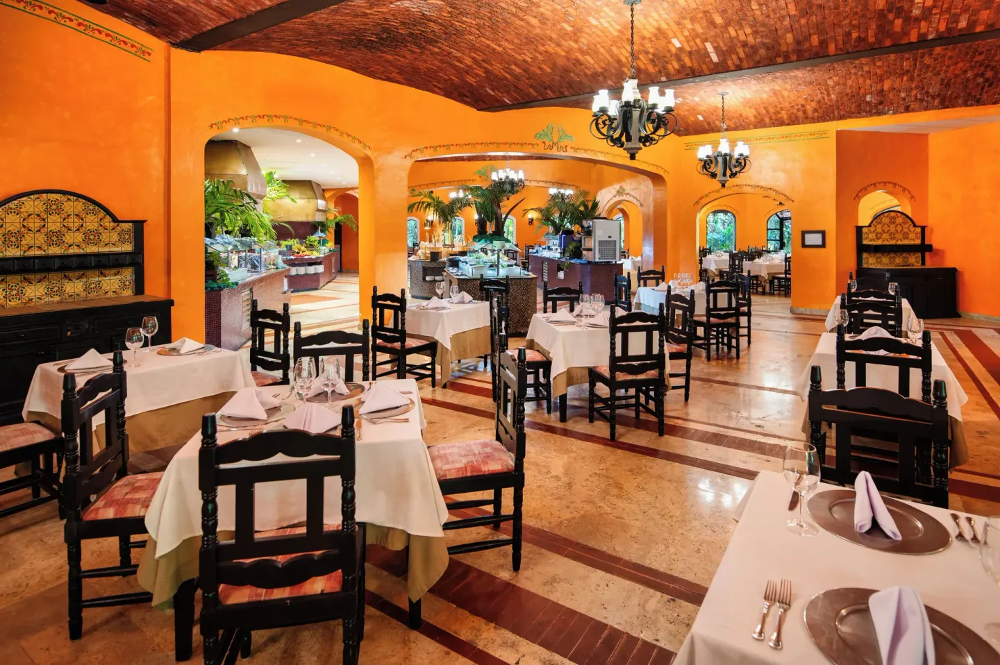 Warm orange restaurant dining room with buffet area at Occidental Cozumel.