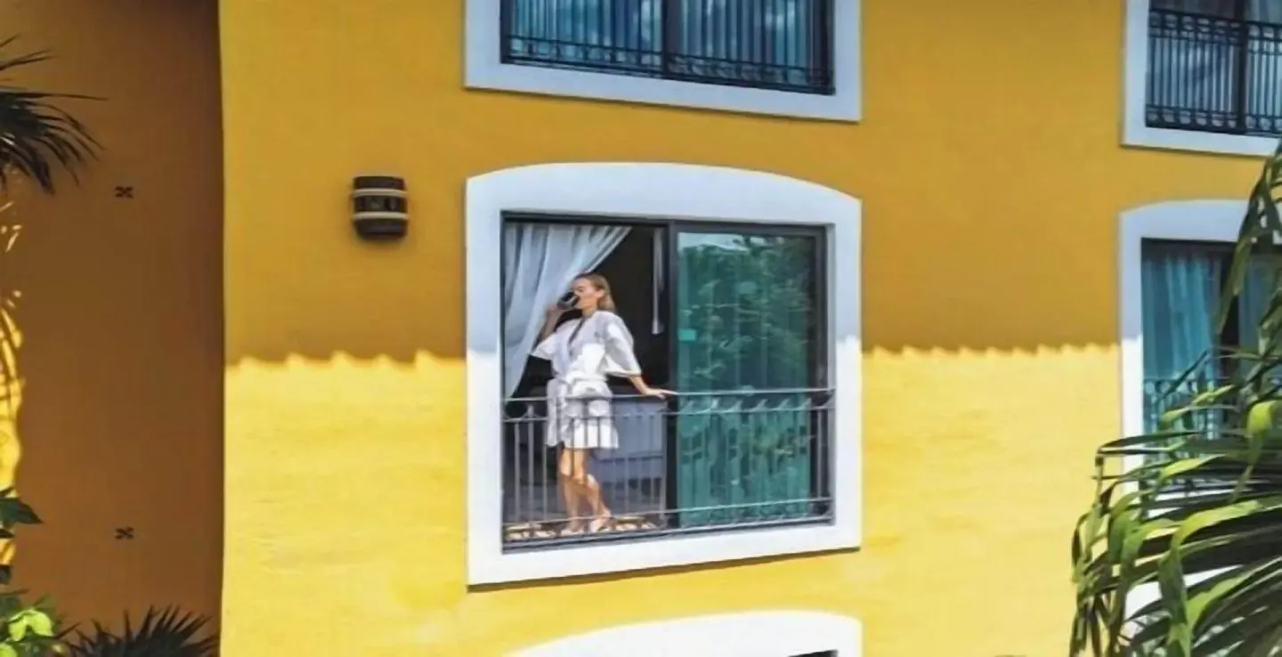 Guest standing on a small balcony outside a yellow room building at Occidental Cozumel.