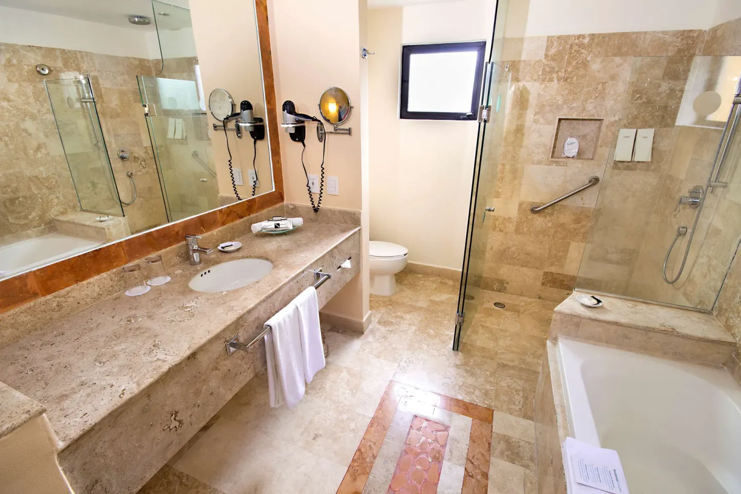 Deluxe room bathroom with vanity, tub and glass shower at Occidental Cozumel.