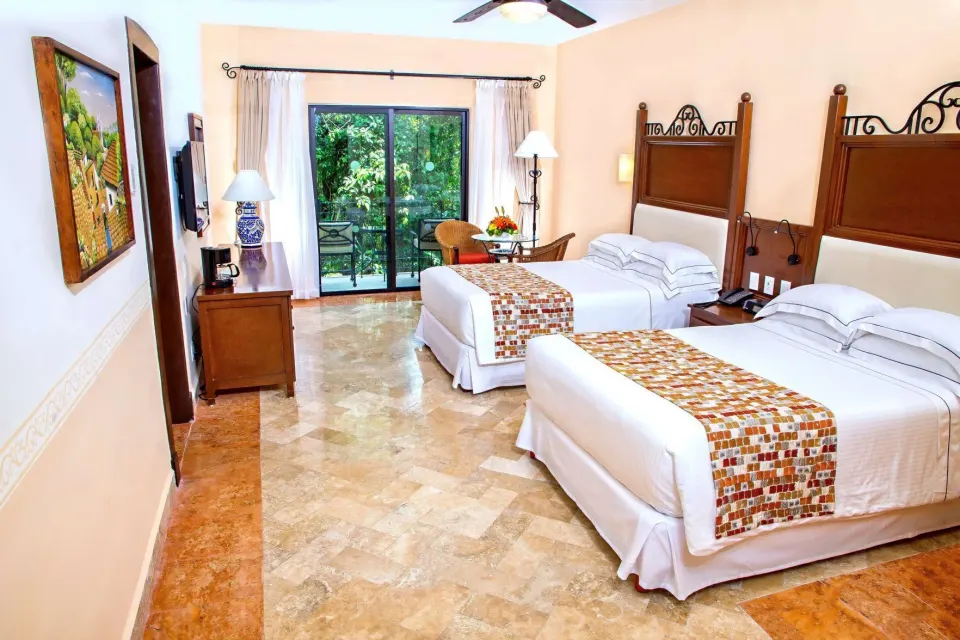 Deluxe Room with two double beds and balcony doors at Occidental Cozumel.