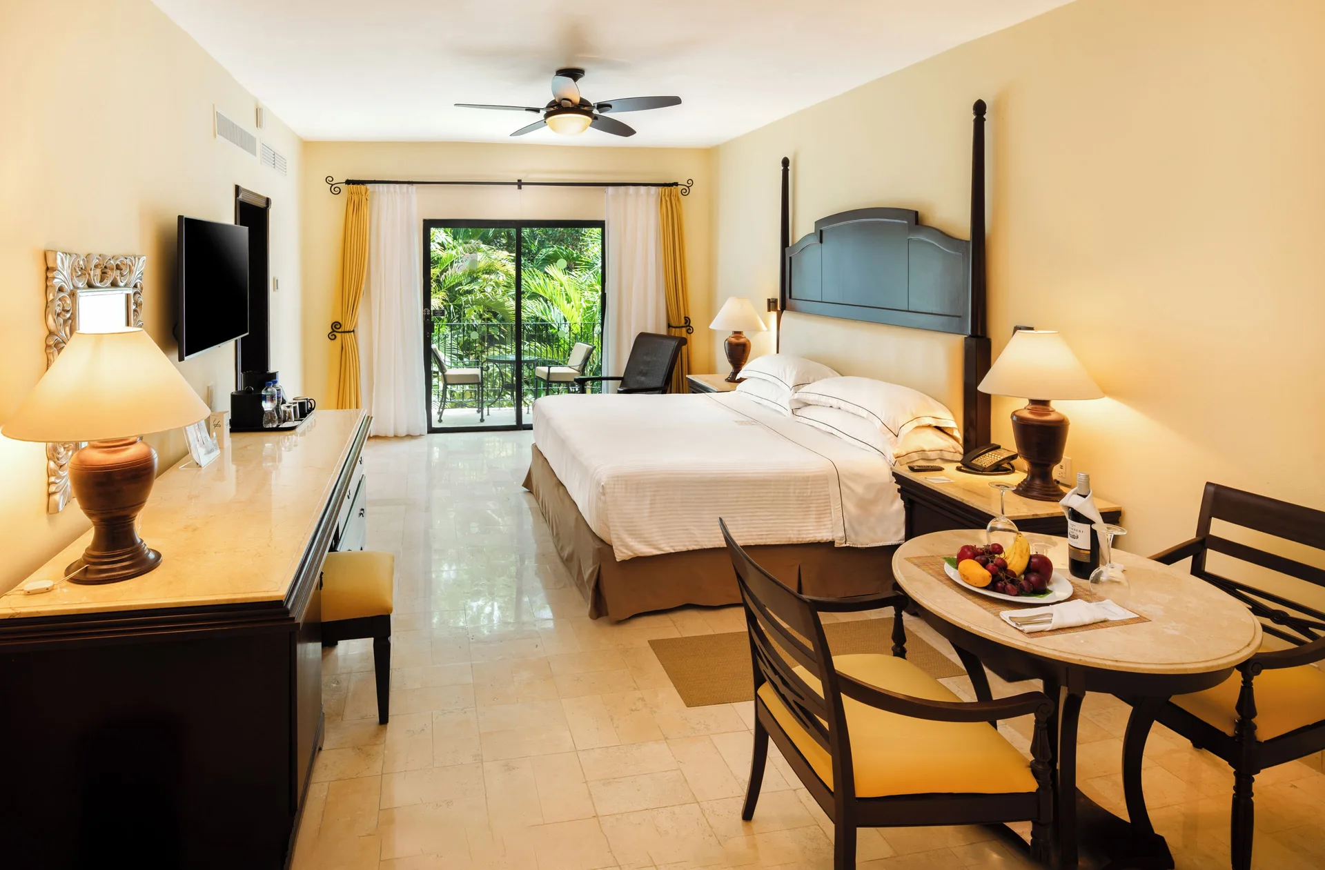 Royal Level Luxury room with king bed and dining table at Occidental Cozumel.