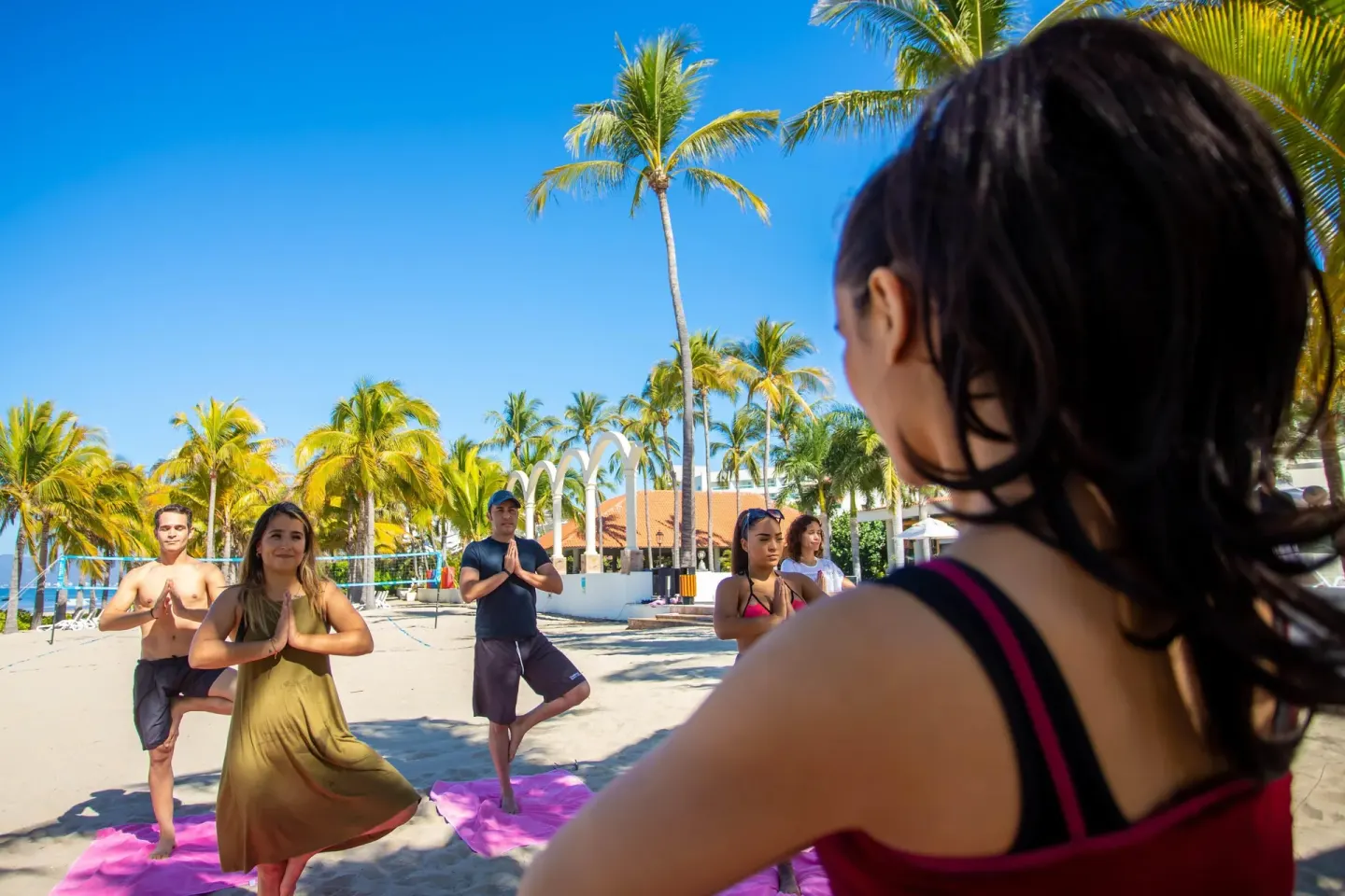 Guests practice beach yoga under palms at Occidental Nuevo Vallarta.
