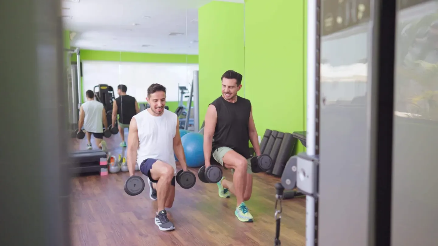 Two guests do dumbbell lunges in the fitness room at Occidental Nuevo Vallarta.