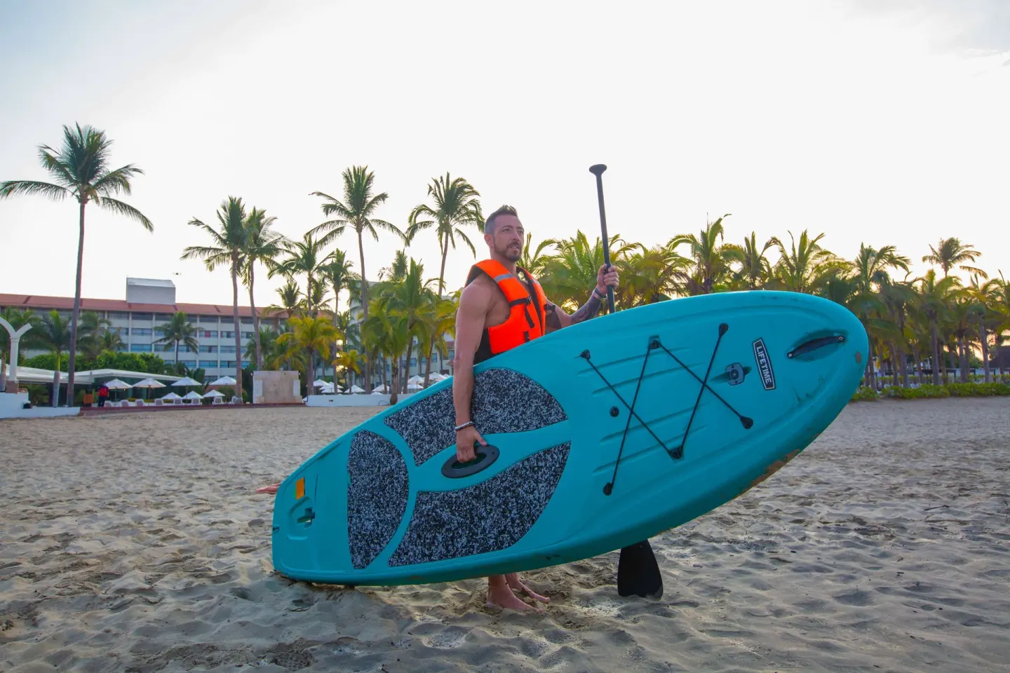 A guest carries a paddleboard on the beach at Occidental Nuevo Vallarta.