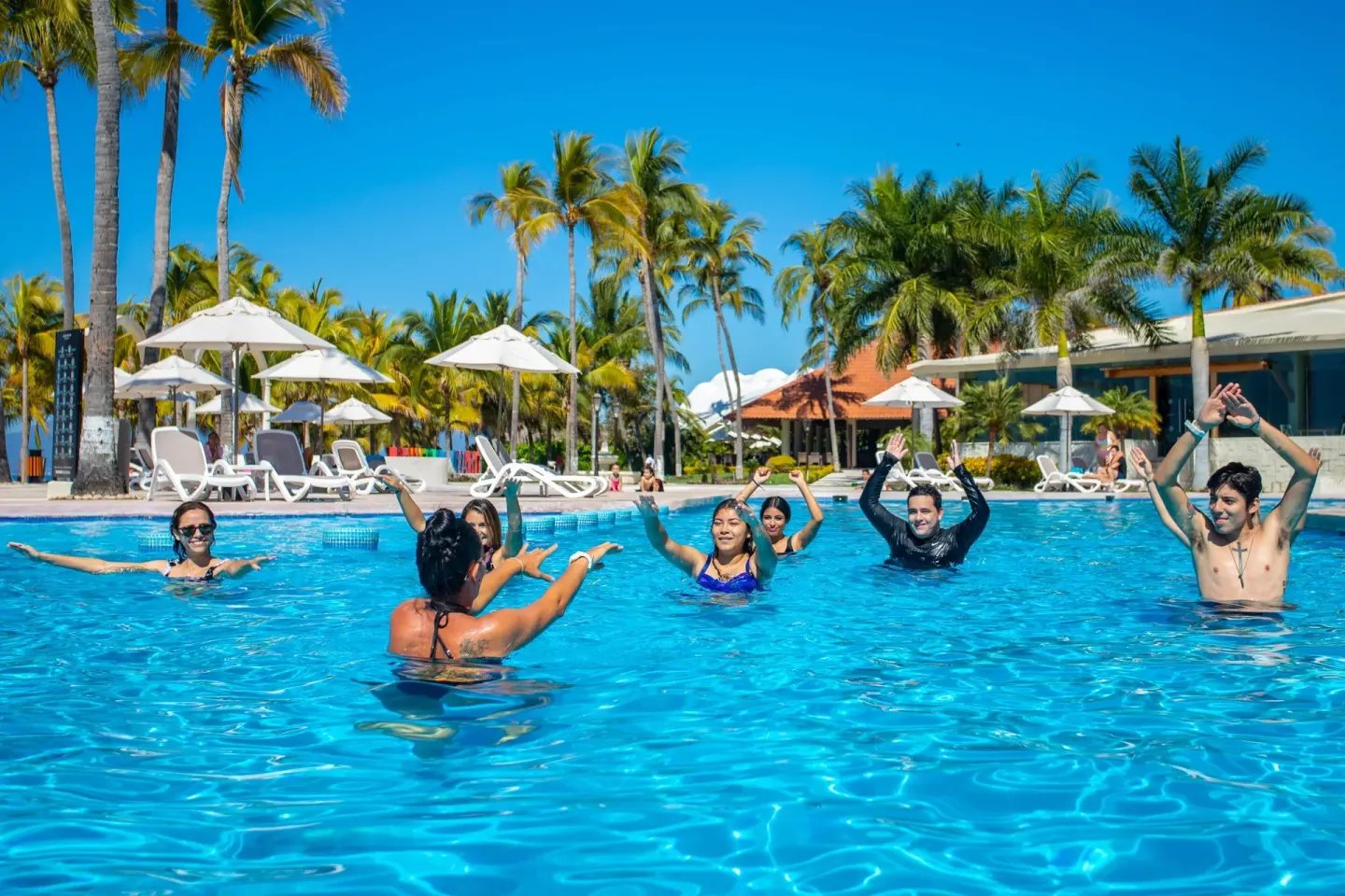 Guests join a pool activity surrounded by palms at Occidental Nuevo Vallarta.