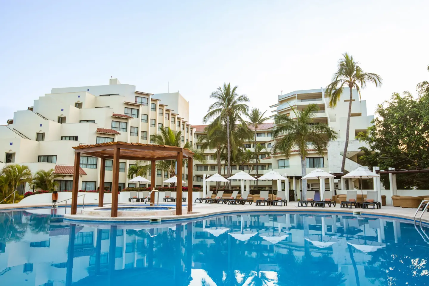 Pool with pergola, loungers, umbrellas, and resort buildings at Occidental Nuevo Vallarta.