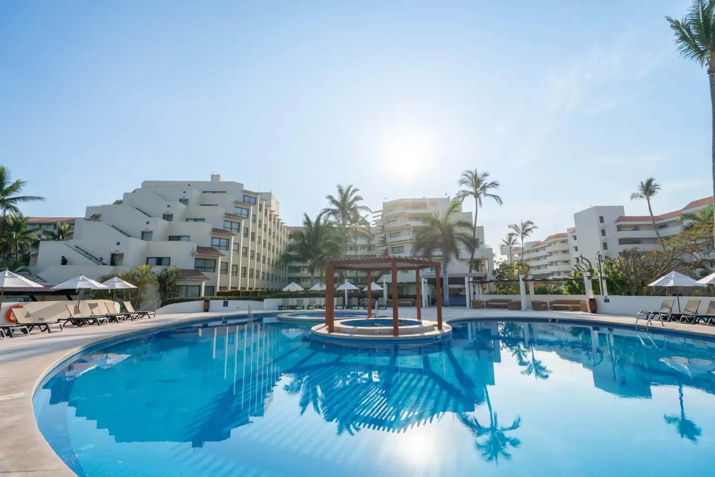 Quiet pool with a small central pergola and resort buildings at Occidental Nuevo Vallarta.