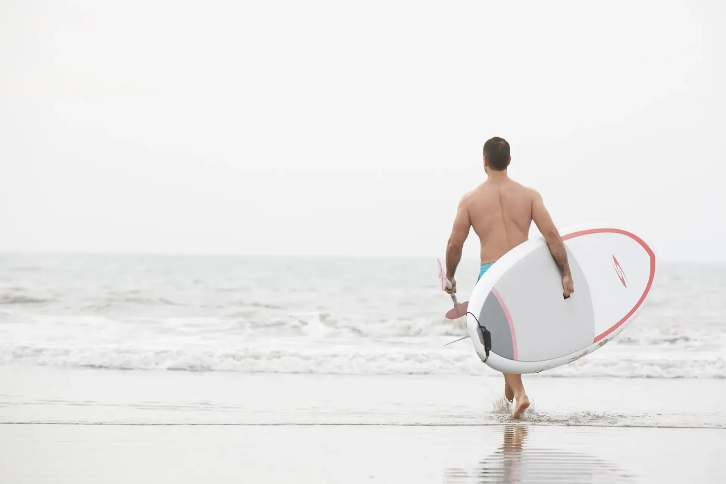 A surfer carries a board into the waves at Occidental Nuevo Vallarta.