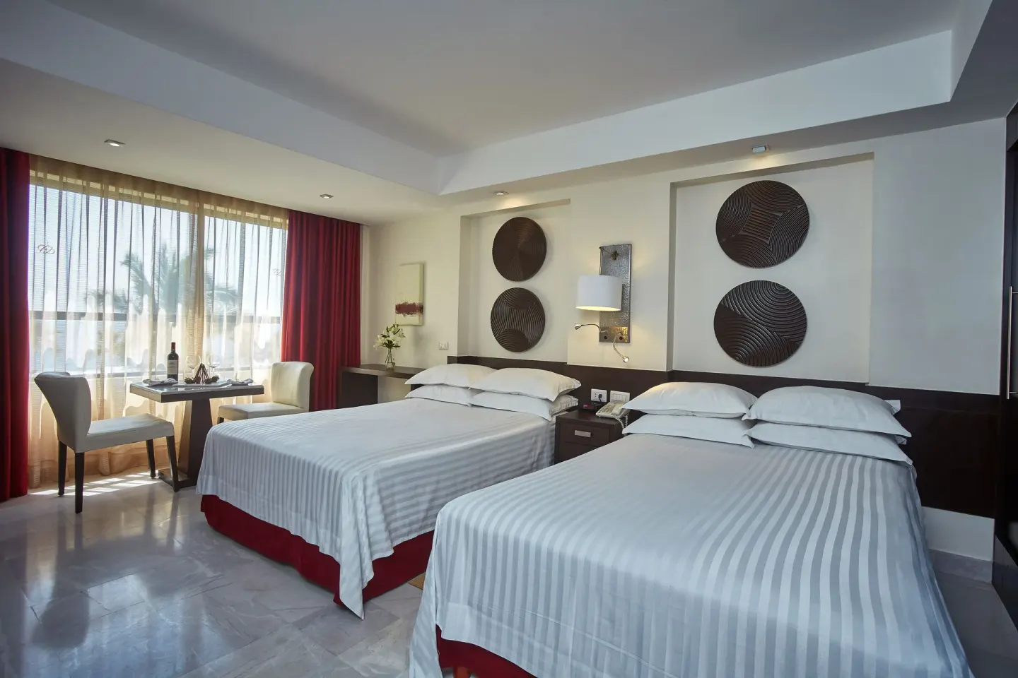 Deluxe Ocean View room with two beds, dining table, and window at Occidental Nuevo Vallarta.