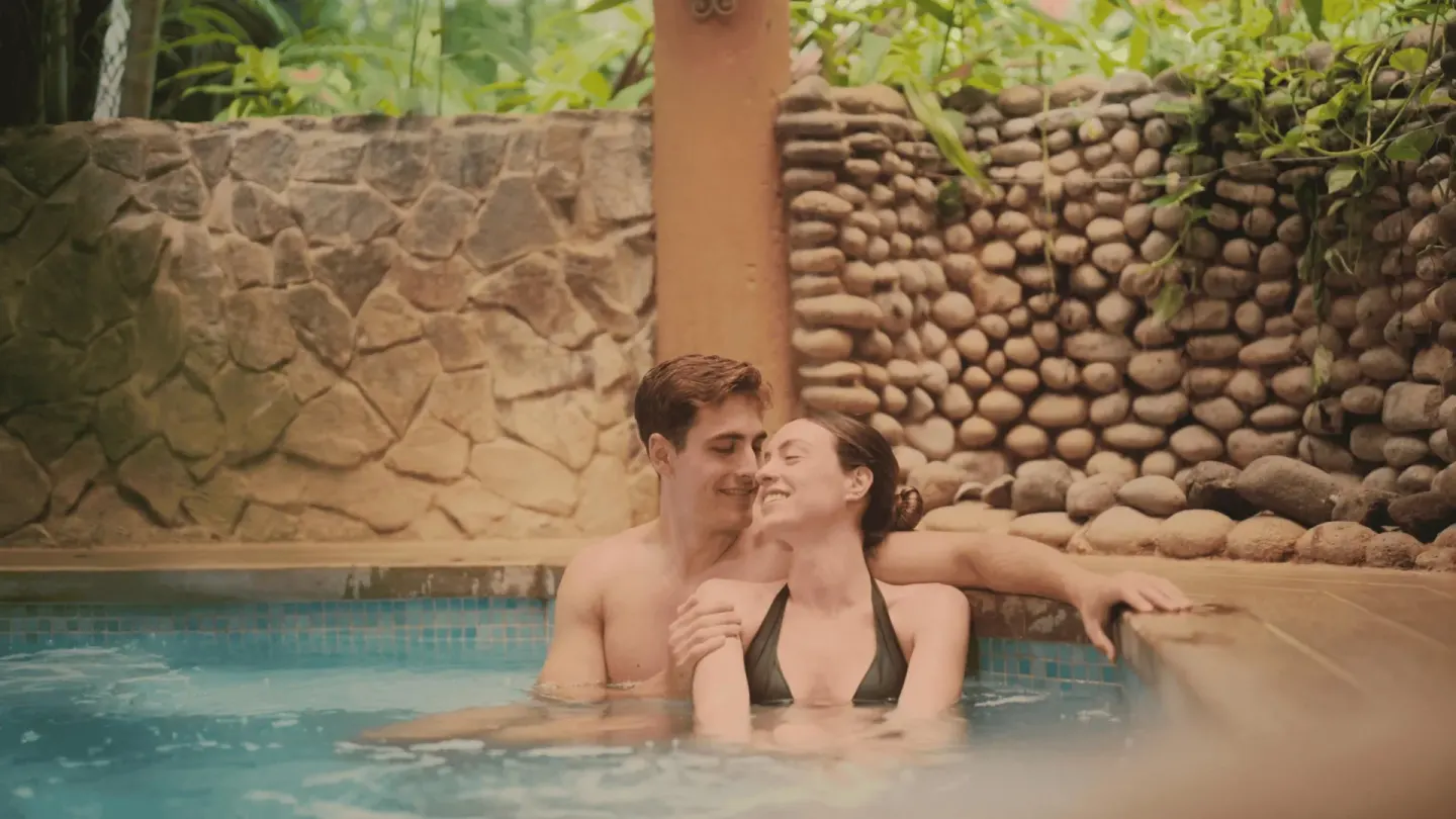 A couple relaxes together in a small pool bordered by stone walls at Occidental Papagayo.