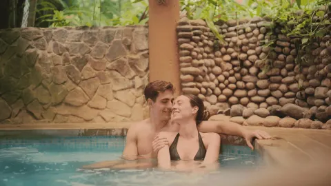 A couple relaxes together in a small pool bordered by stone walls at Occidental Papagayo.