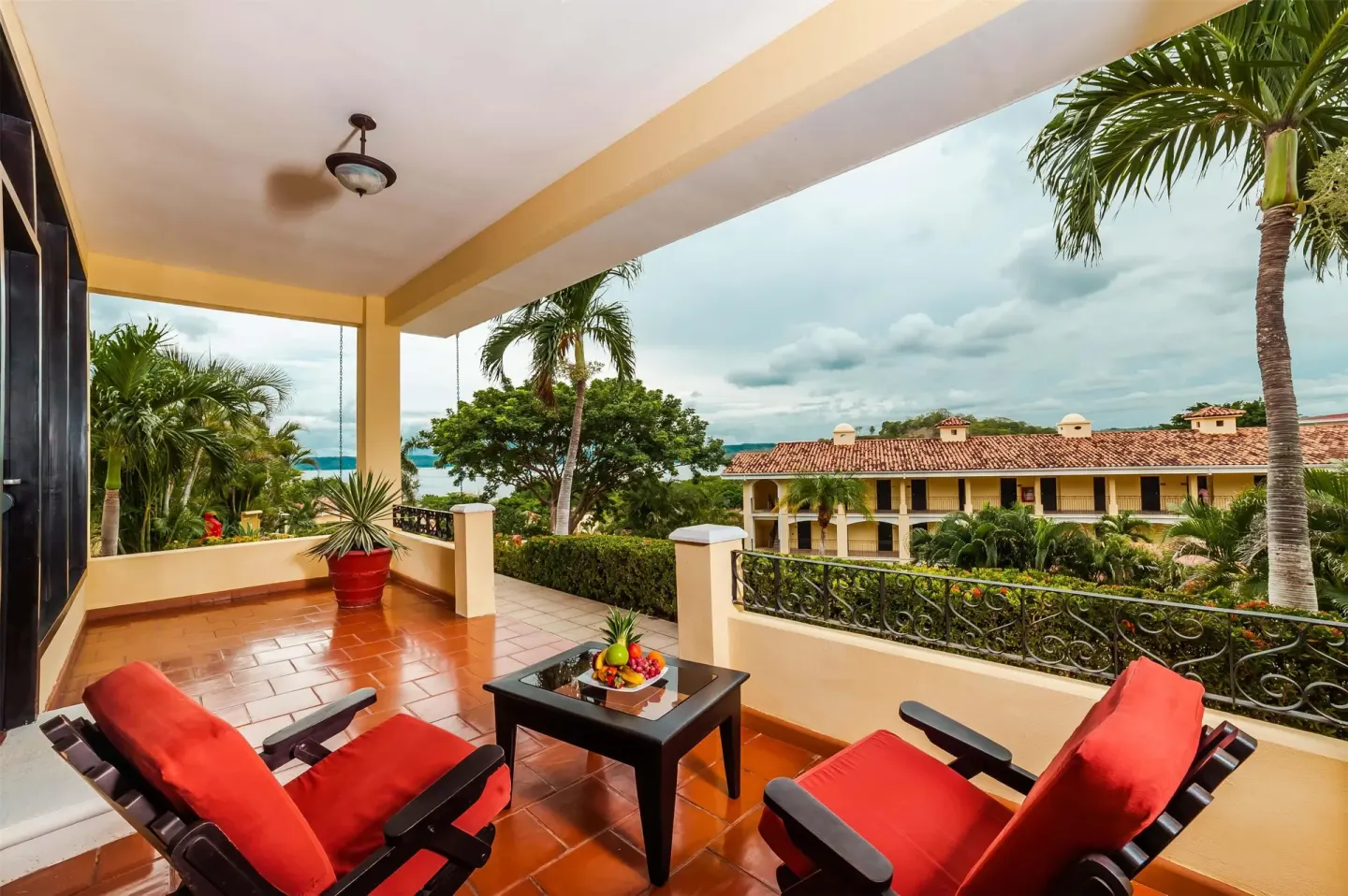 Covered terrace with red-cushioned chairs and resort view at Occidental Papagayo.