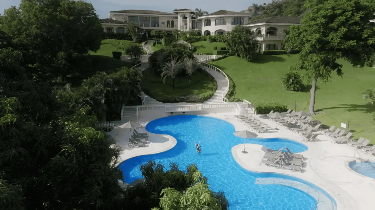 Curved outdoor pool and landscaped hillside buildings at Occidental Papagayo.
