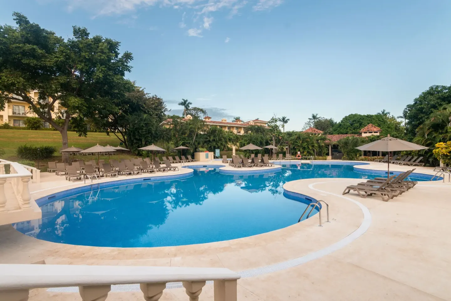 Curved resort pool with loungers and umbrellas at Occidental Papagayo.