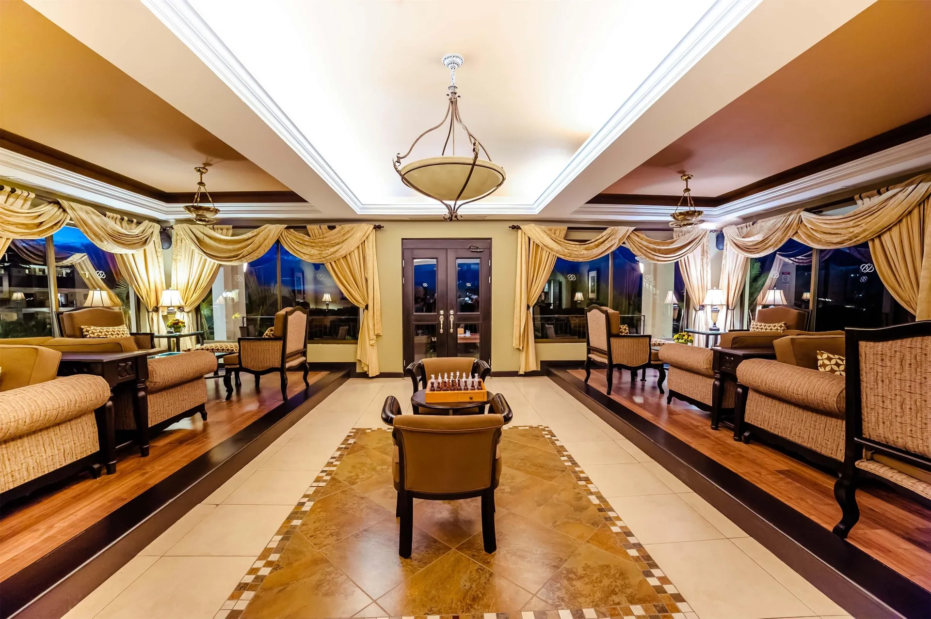 Elegant lounge with armchairs, curtains, and a chess table at Occidental Papagayo.
