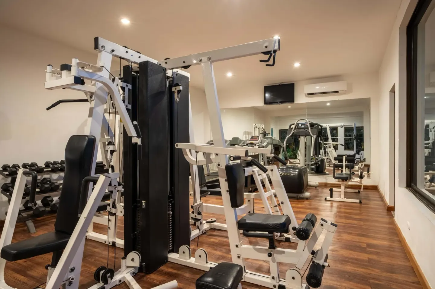 Fitness room with weight machines, dumbbells, mirrors, and wood flooring at Occidental Papagayo.