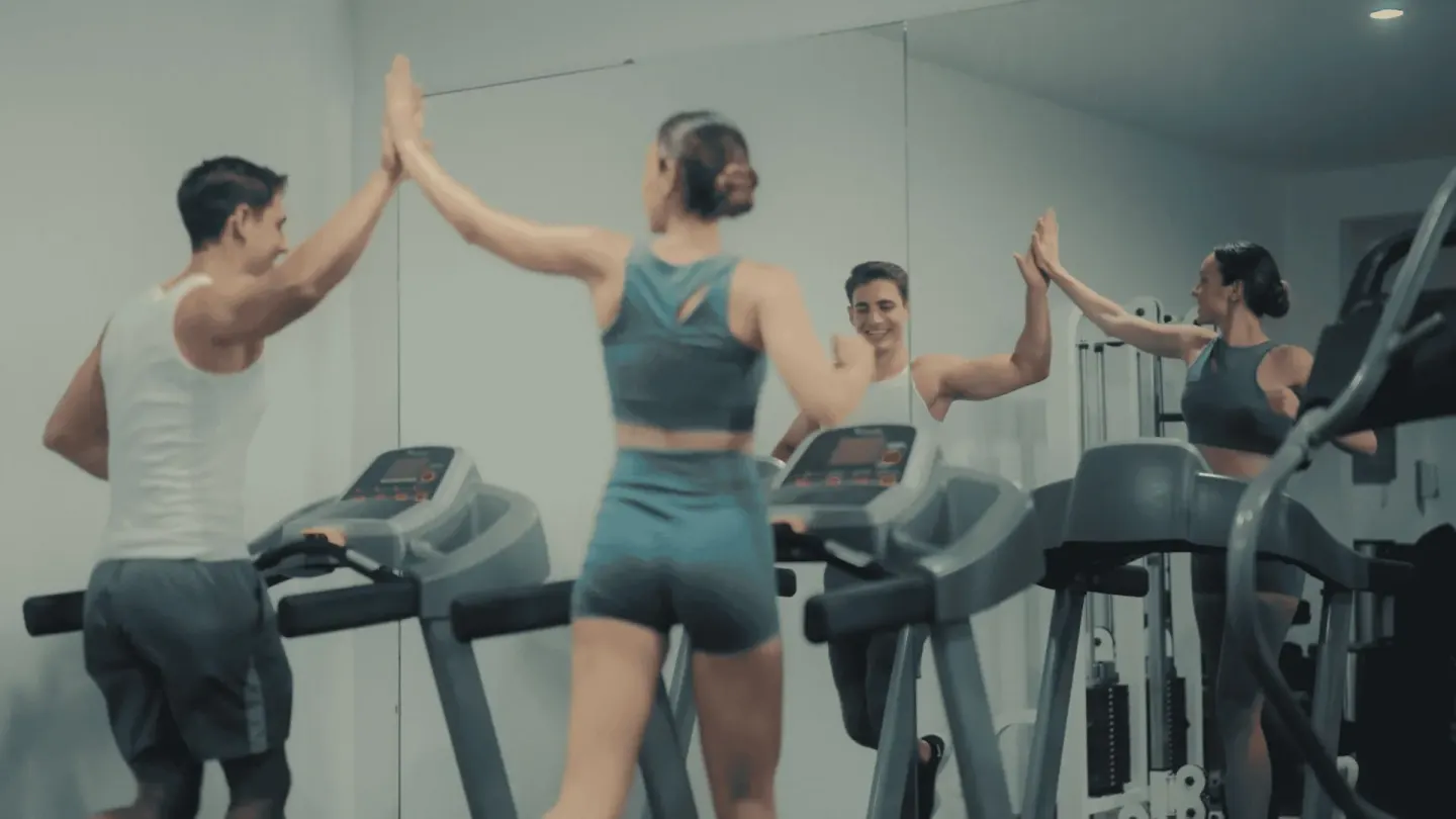 Two guests high-five beside treadmills in the fitness room at Occidental Papagayo.