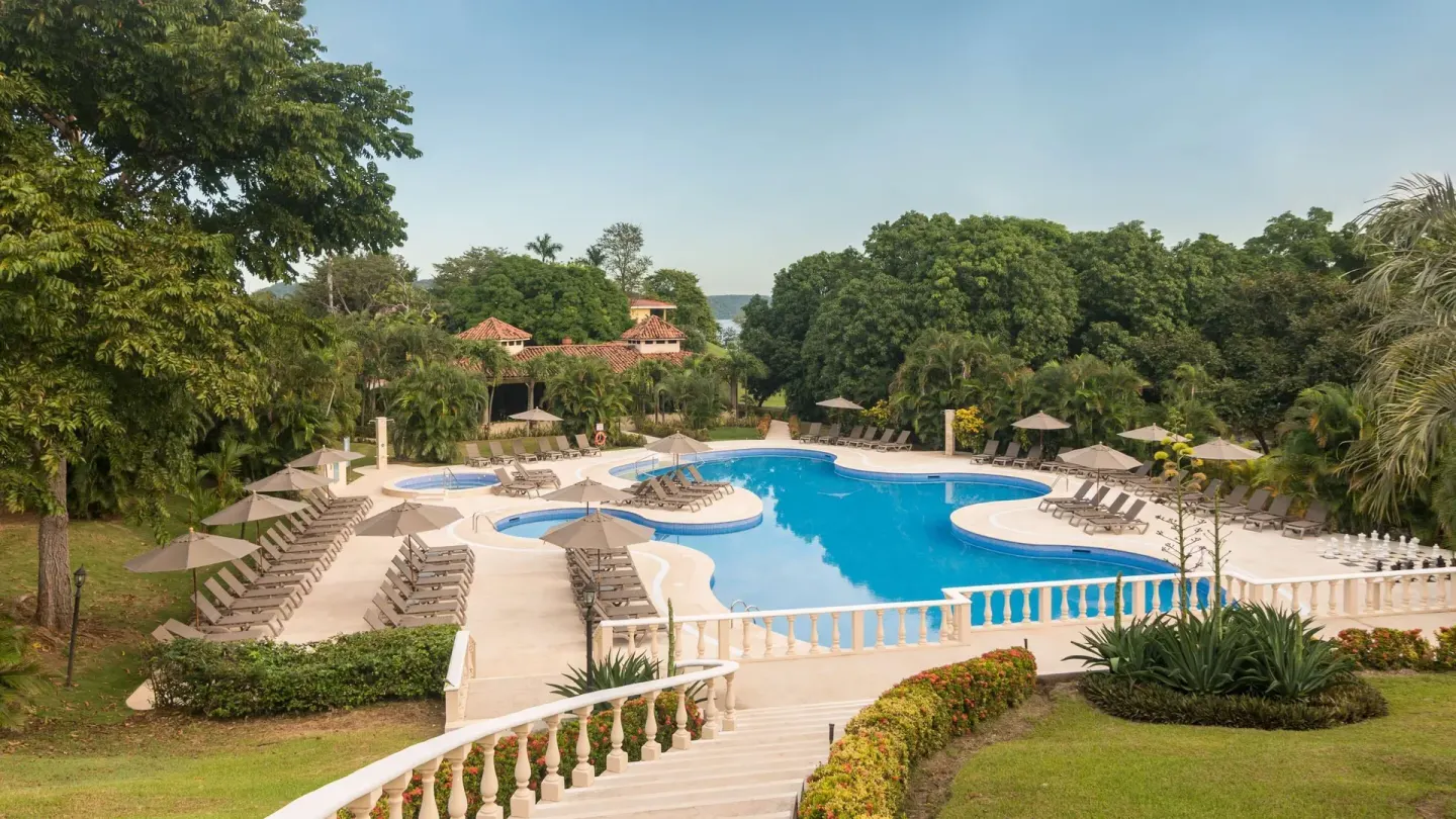 Main pool with umbrellas, loungers, and tropical gardens at Occidental Papagayo.