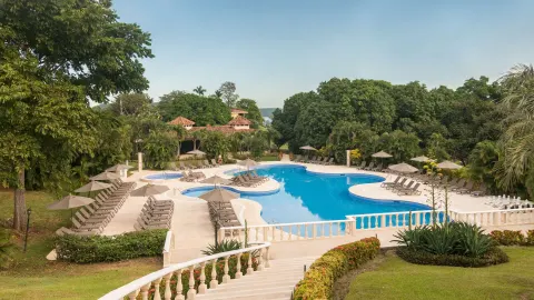 Main pool with umbrellas, loungers, and tropical gardens at Occidental Papagayo.