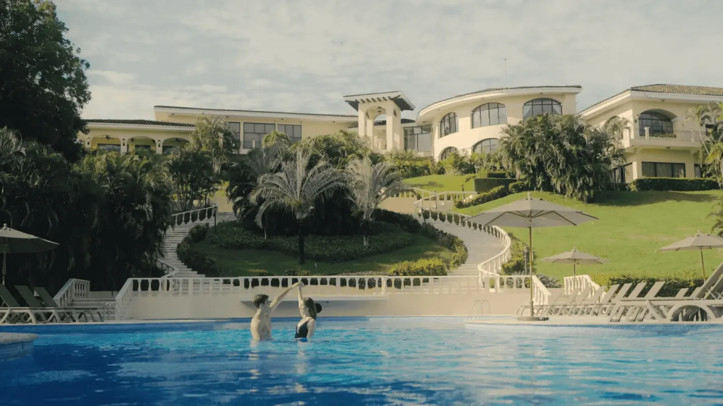 Guests in the pool below hillside buildings and gardens at Occidental Papagayo.