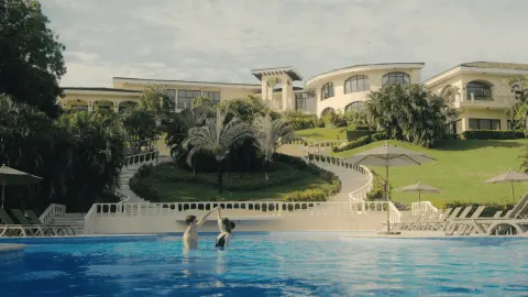 Guests in the pool below hillside buildings and gardens at Occidental Papagayo.