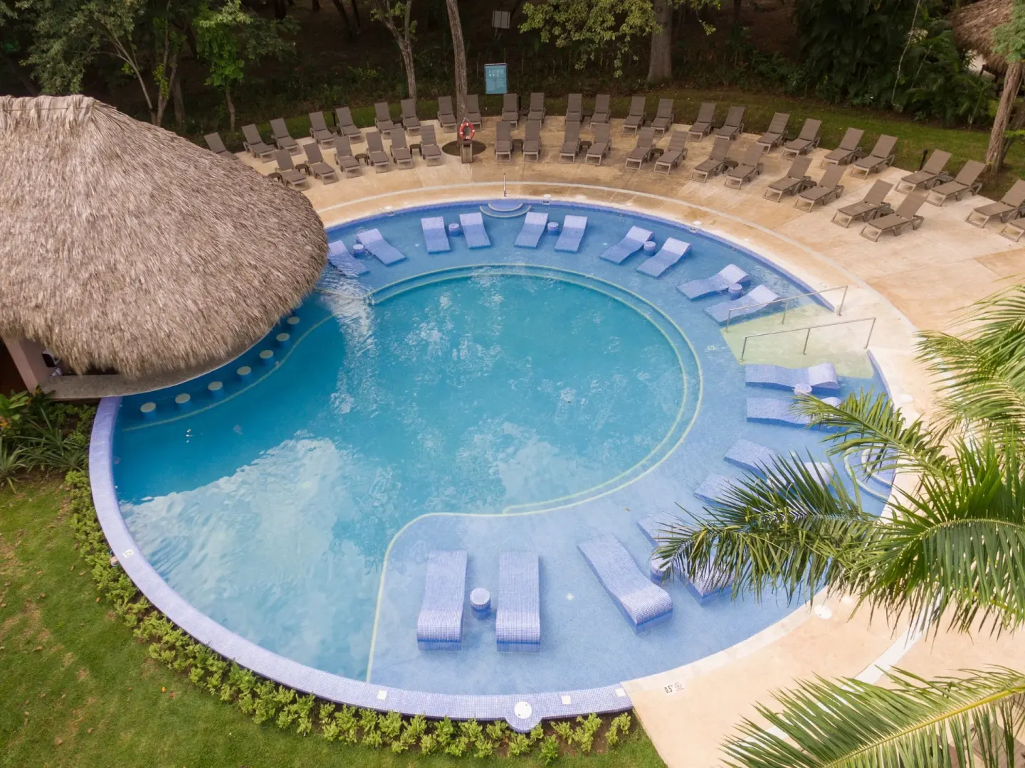 Round pool with submerged loungers and a thatched roof at Occidental Papagayo.