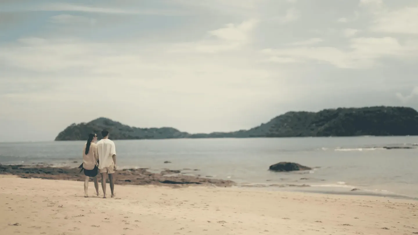 Couple walking on a sandy beach with calm water at Occidental Papagayo.