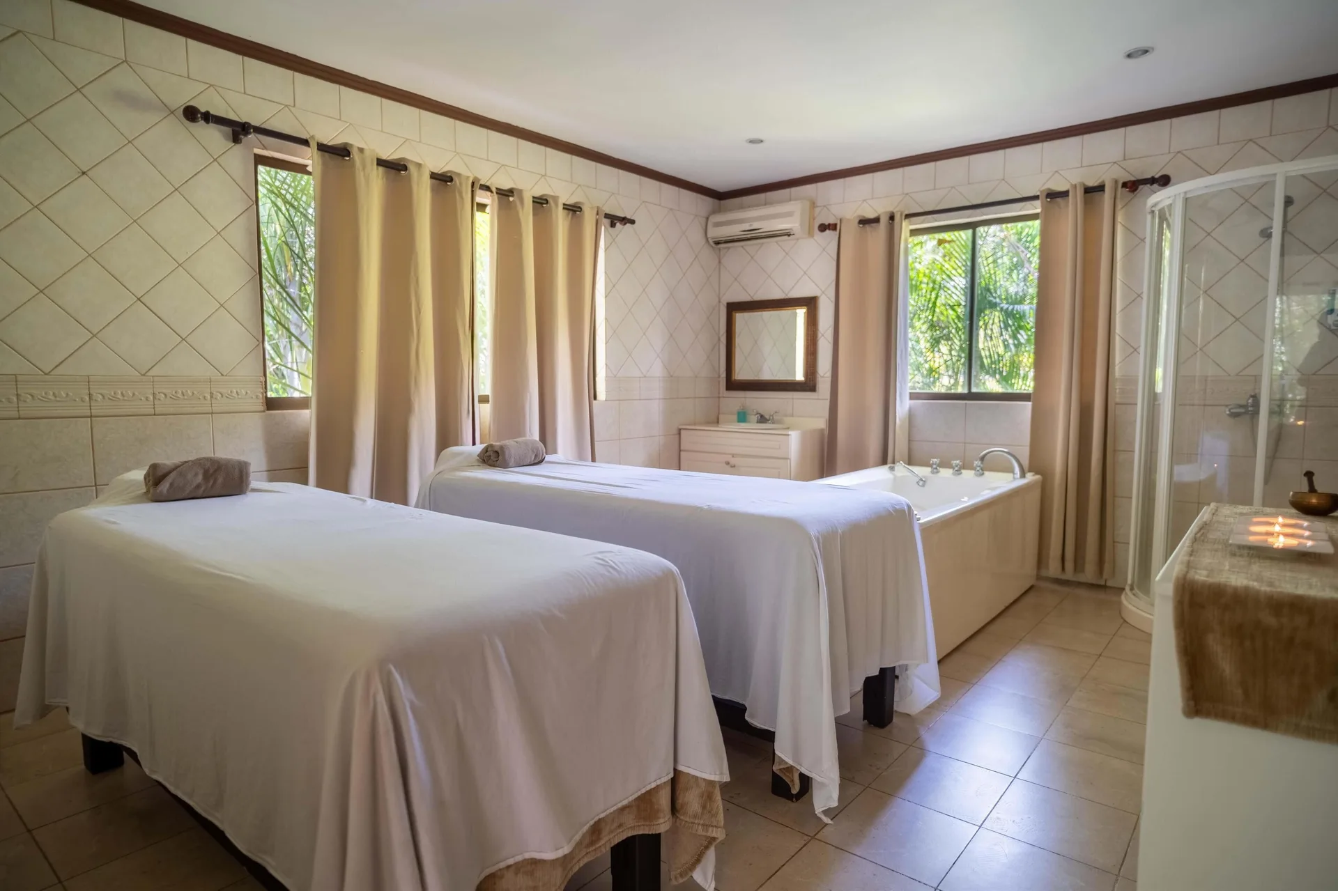 Spa room with two massage tables, bathtub, and shower at Occidental Papagayo.