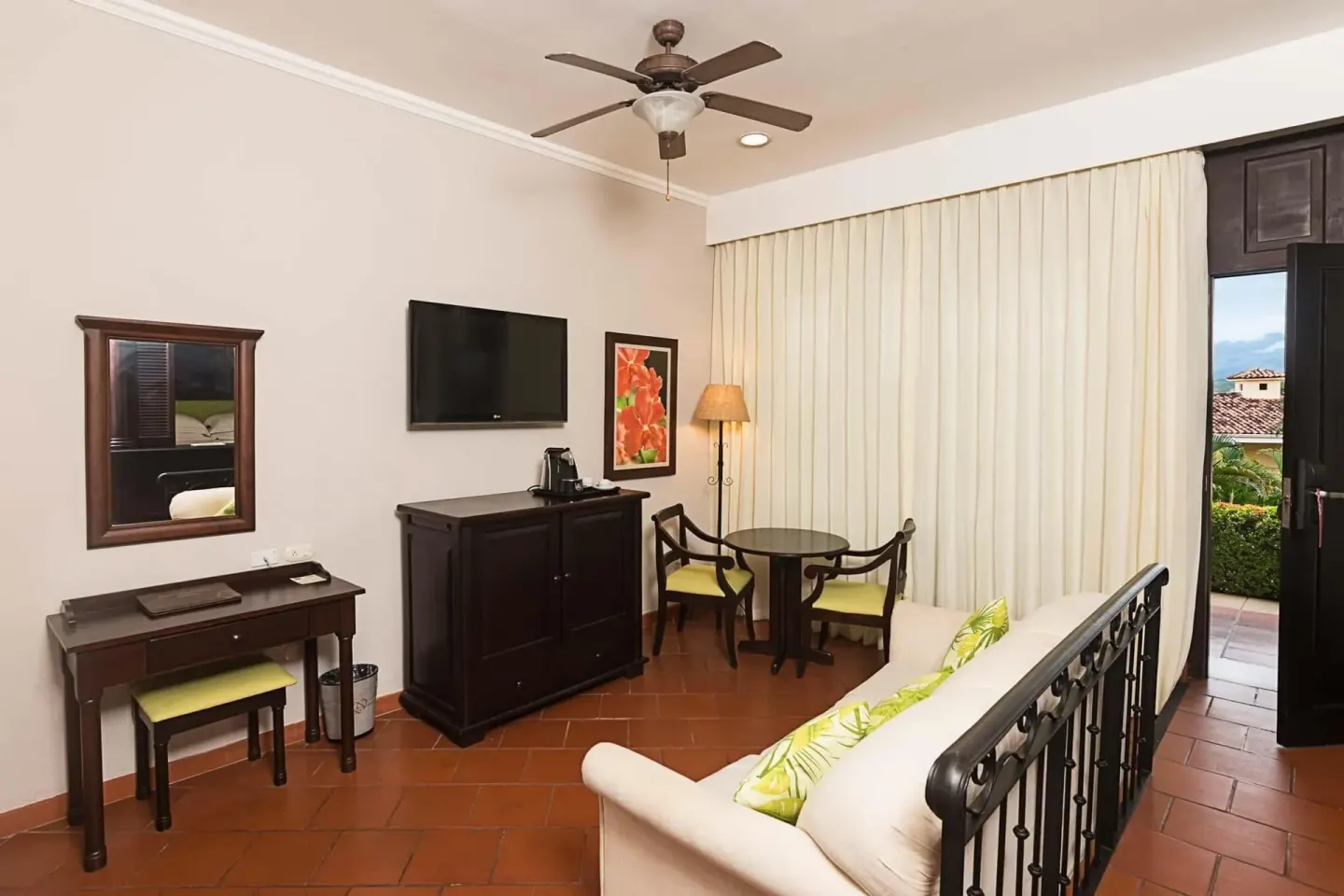 Suite sitting area with TV, desk and terrace door at Occidental Papagayo.
