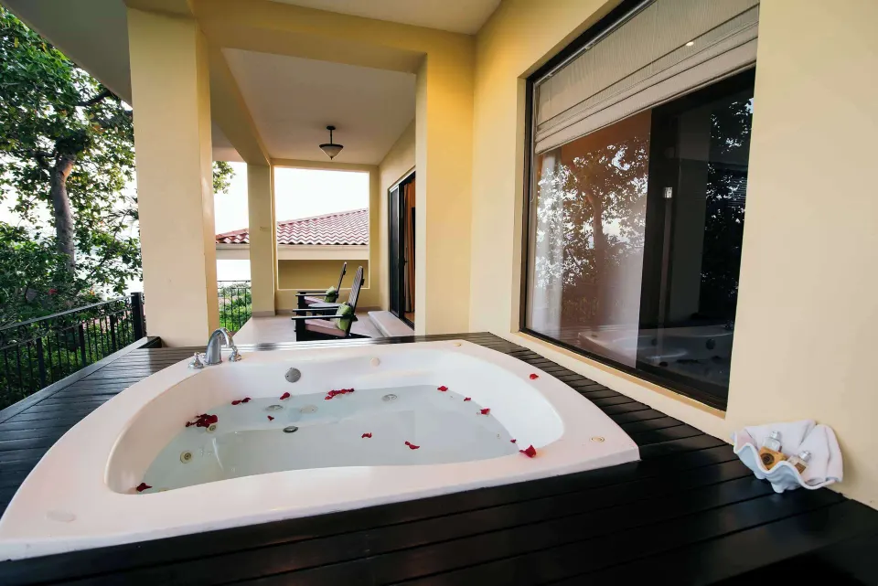 Terrace whirlpool tub with rose petals and a large window at Occidental Papagayo.